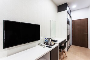 A hotel room with a large flat-screen TV, a desk with a phone, remote controls, and toiletries. - Casuarina@Pangkor (Pangkor Island)