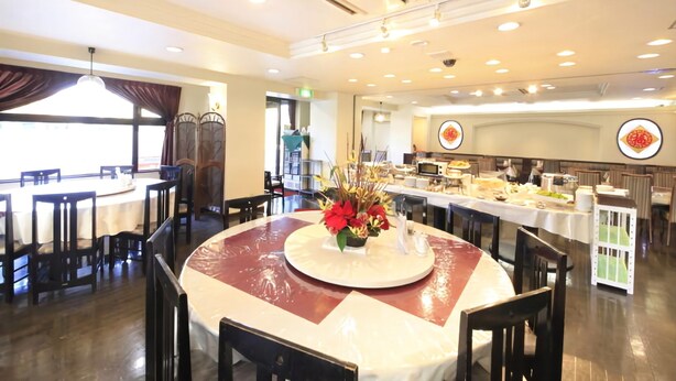 A restaurant with round tables, a buffet area, and a decorative centerpiece.