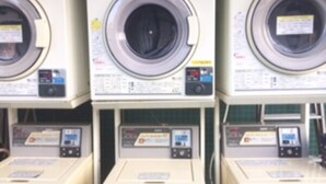 A row of stacked washing machines in a commercial setting.