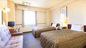 A hotel room with two beds, a desk, a chair, a TV, and a window with curtains.