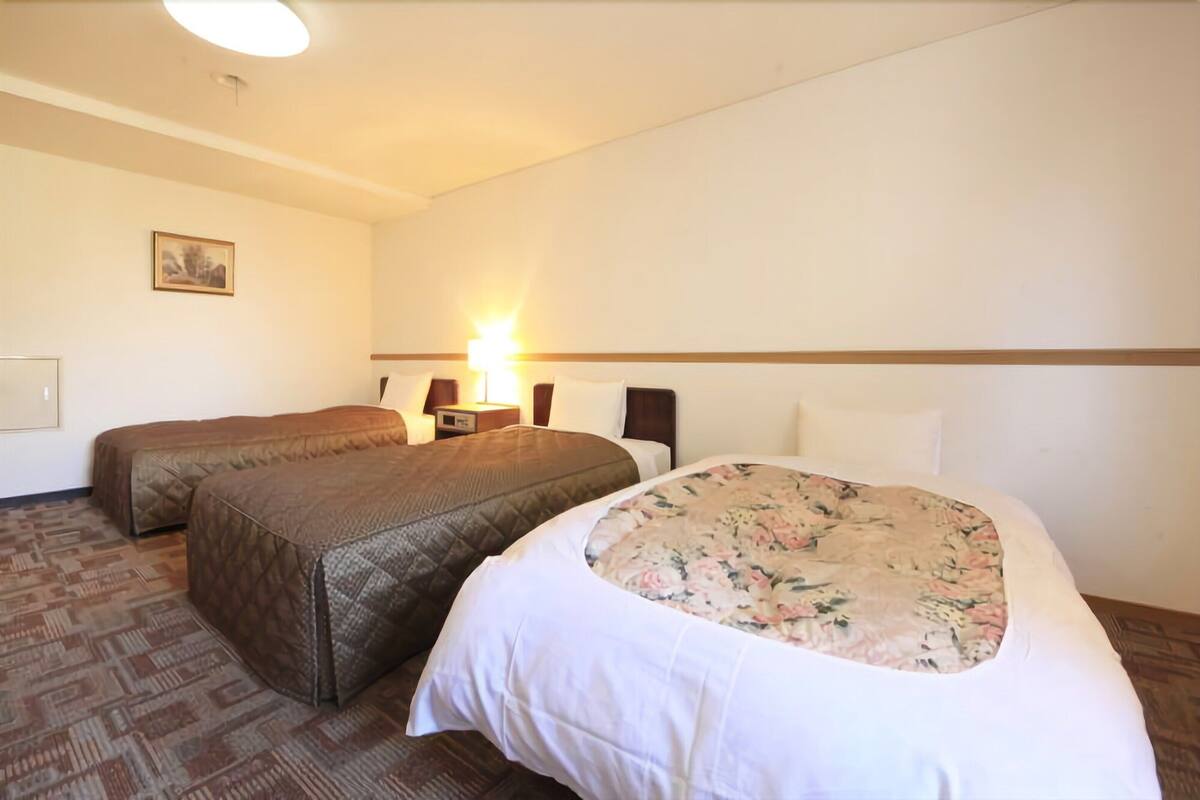 Habitación de hotel con dos camas, una mesita de noche con lámpara y un cuadro en la pared.