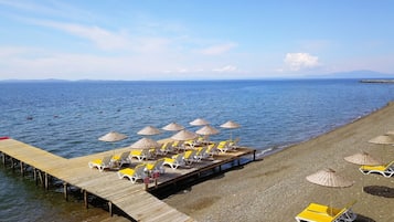 En privat strand, liggestole, parasoller, volleyball