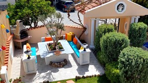 Un espace patio comprenant une table en pierre, des sièges d’extérieur, une petite fontaine et une piscine.