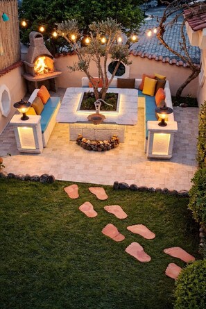 An outdoor seating area with stone flooring, a fire feature, and a decorative tree. - Dalyan Palace (Ortaca)