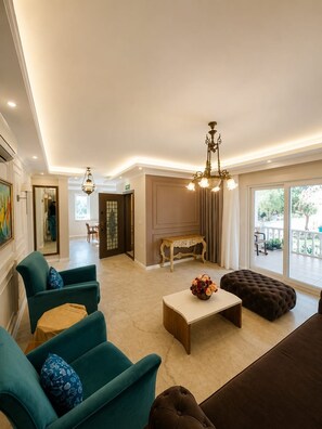 A spacious living room with a sofa set, a coffee table, and a chandelier. - Dalyan Palace (Ortaca)