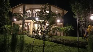 A two-story building with a balcony, surrounded by trees and a well-maintained lawn.