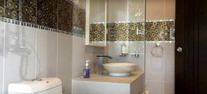 A bathroom with a toilet, a sink, and a shower area.