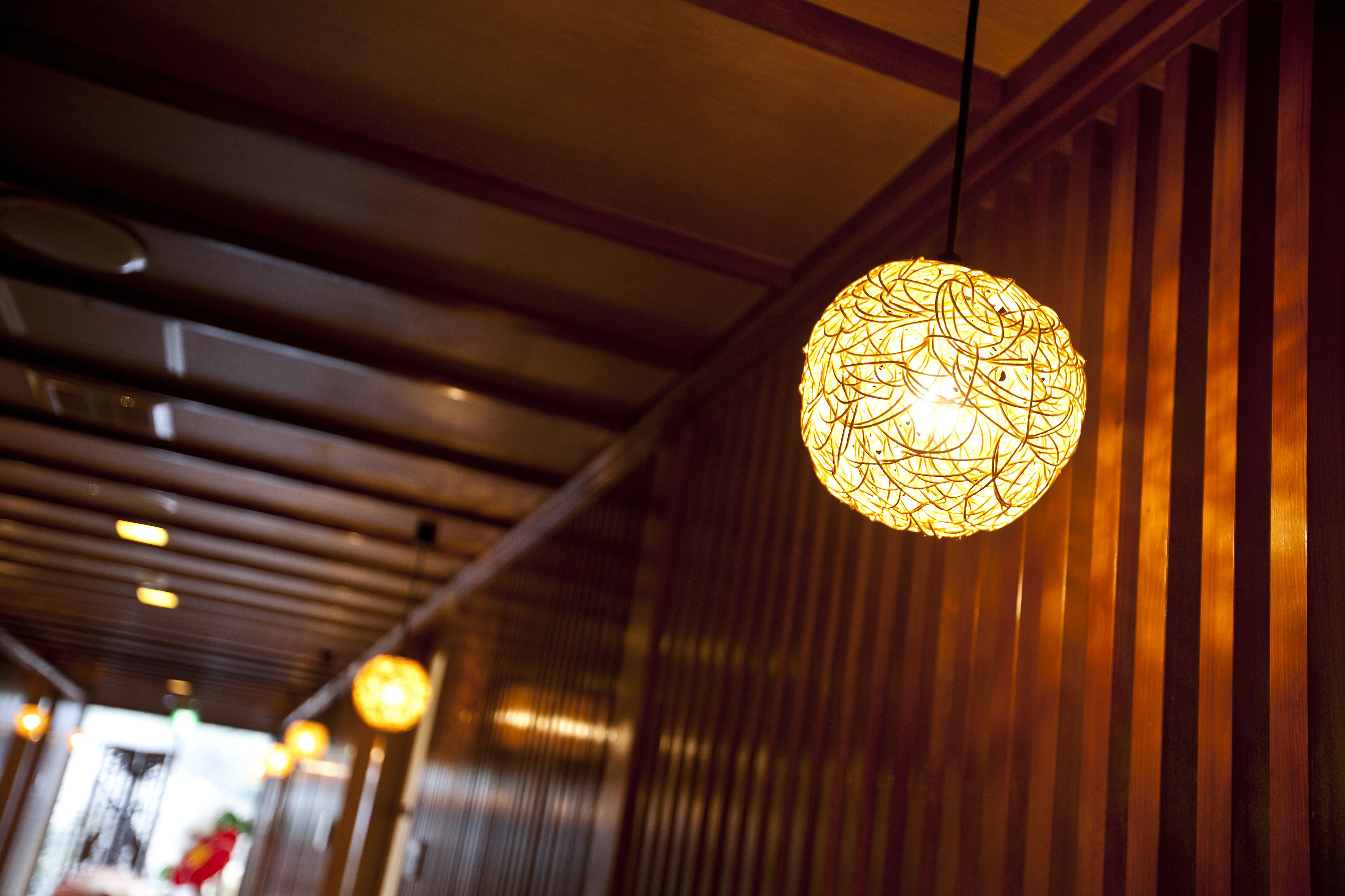 A corridor with hanging spherical light fixtures and wooden paneling.