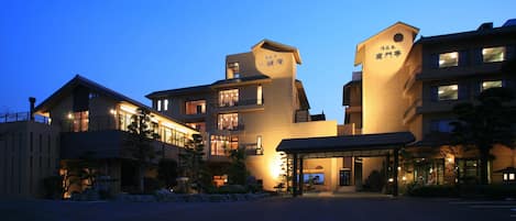 Un hotel de varios pisos con un diseño arquitectónico moderno, que cuenta con una entrada destacada y una zona de espera cubierta.