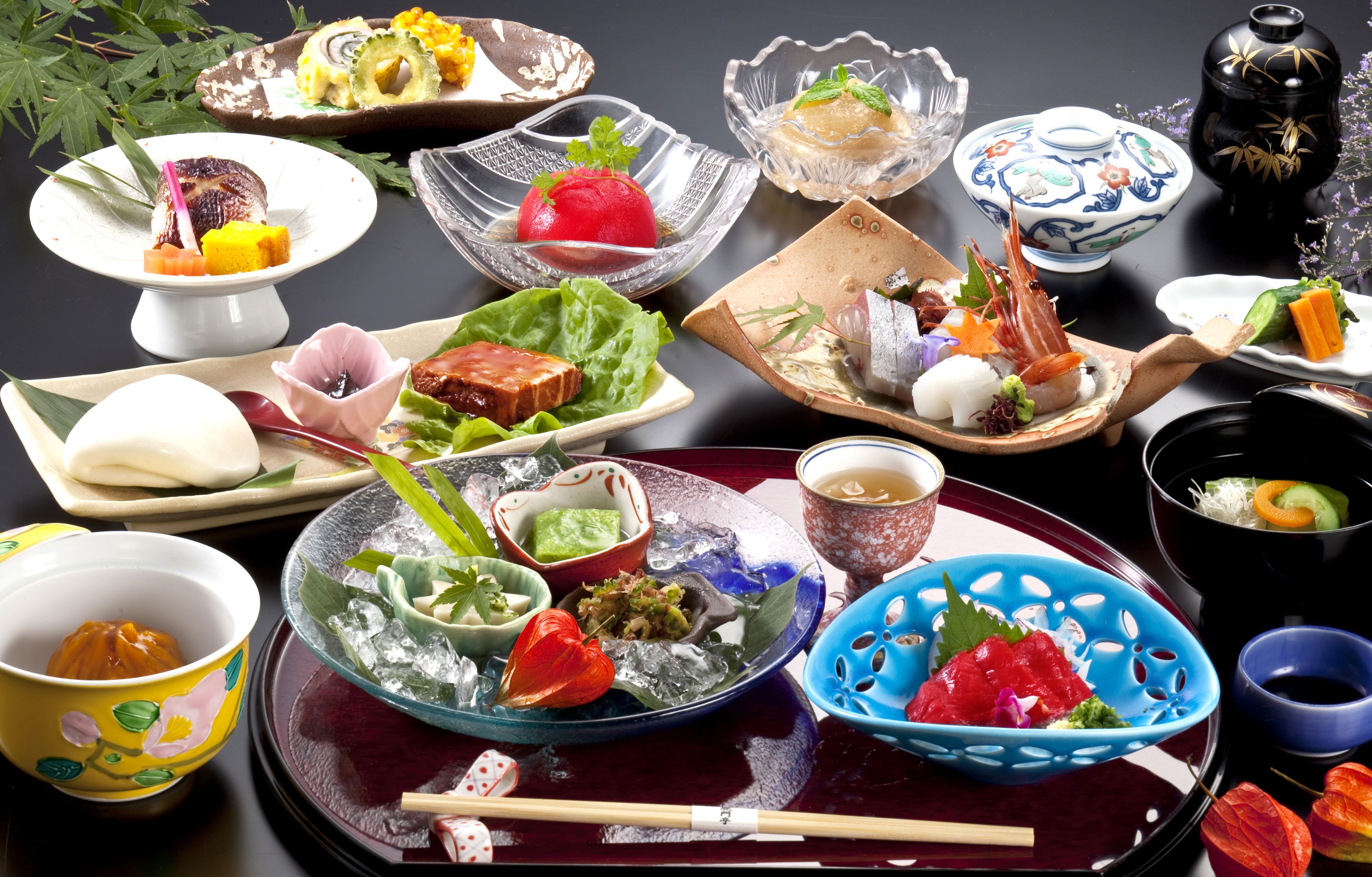Une variété de plats japonais sont disposés sur une table, notamment des sushis, des sashimis et d’autres mets raffinés, accompagnés de baguettes et de bols.