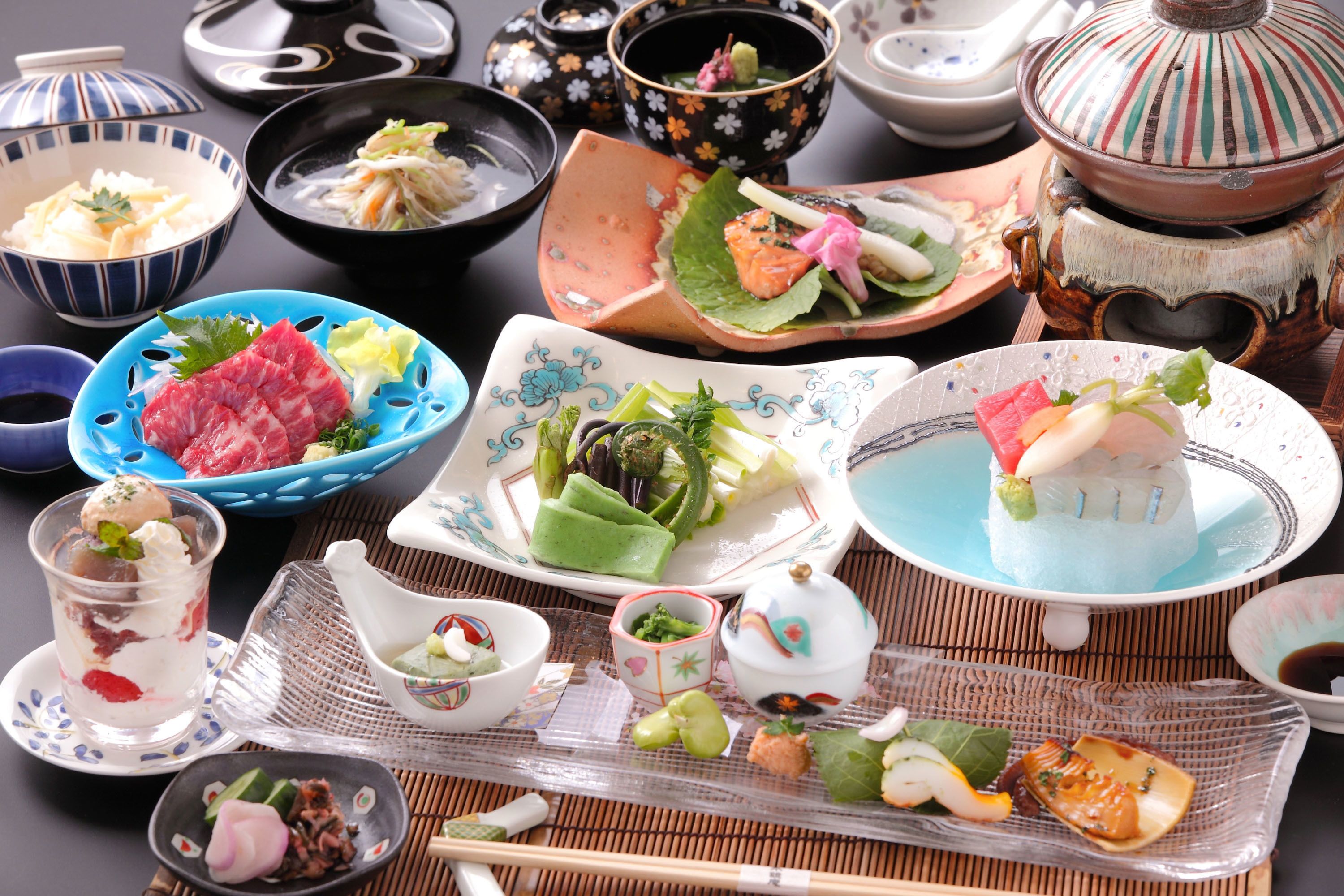 Een verscheidenheid aan traditionele Japanse gerechten, waaronder sushi, sashimi en andere lekkernijen, gepresenteerd in diverse schalen en borden.