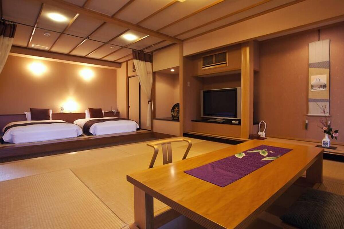 Quarto de hotel com cama, televisão, mesa e cadeira.