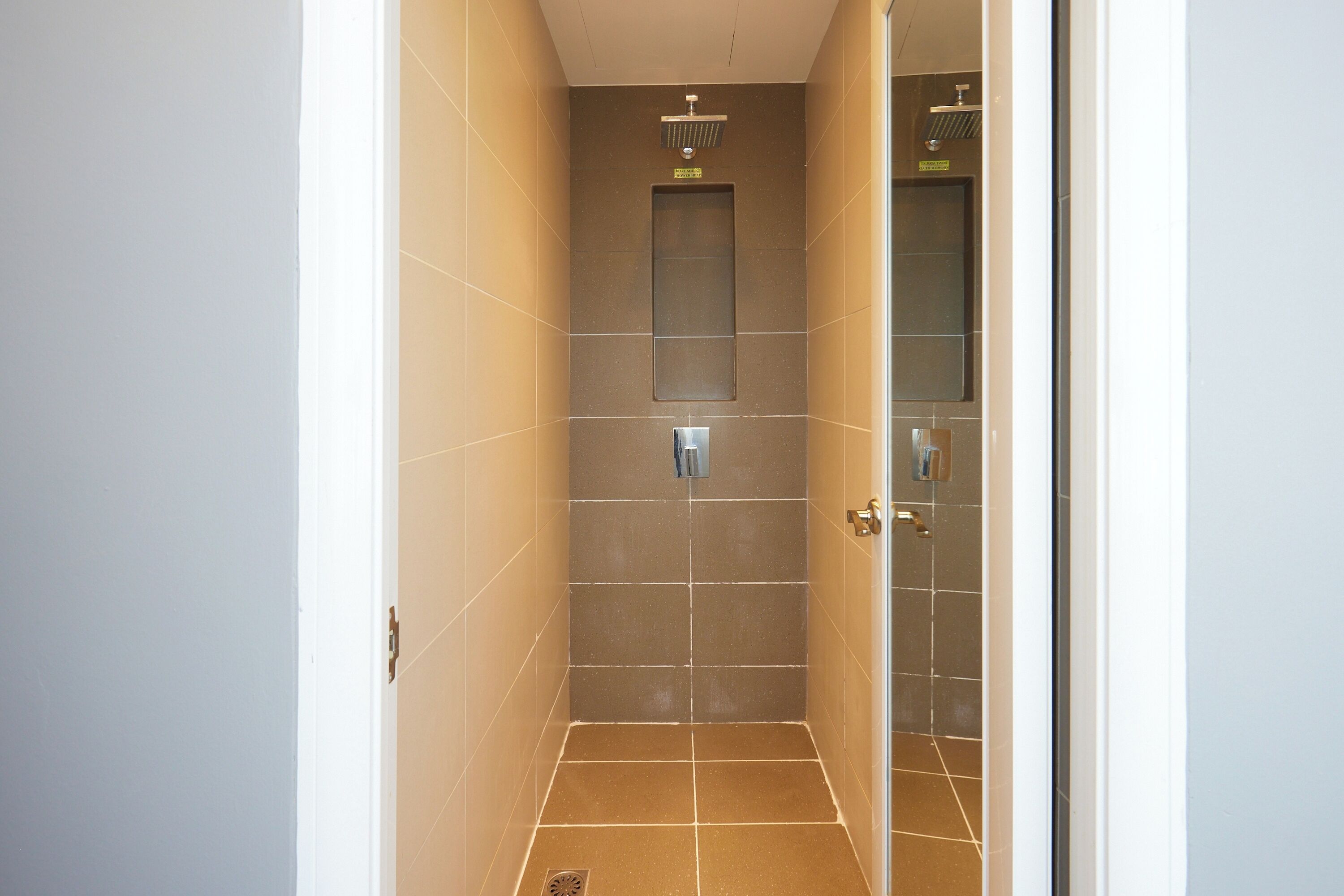A narrow, tiled shower stall with a showerhead and a small window.