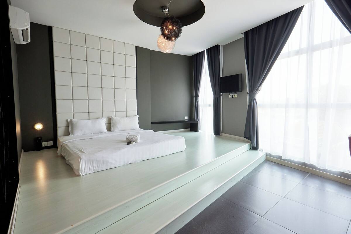 Une chambre moderne avec un grand lit, un luminaire au plafond et une grande fenêtre avec des rideaux.