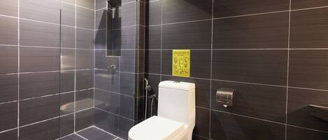 A modern bathroom with dark tiles, a glass-enclosed shower, and a toilet.