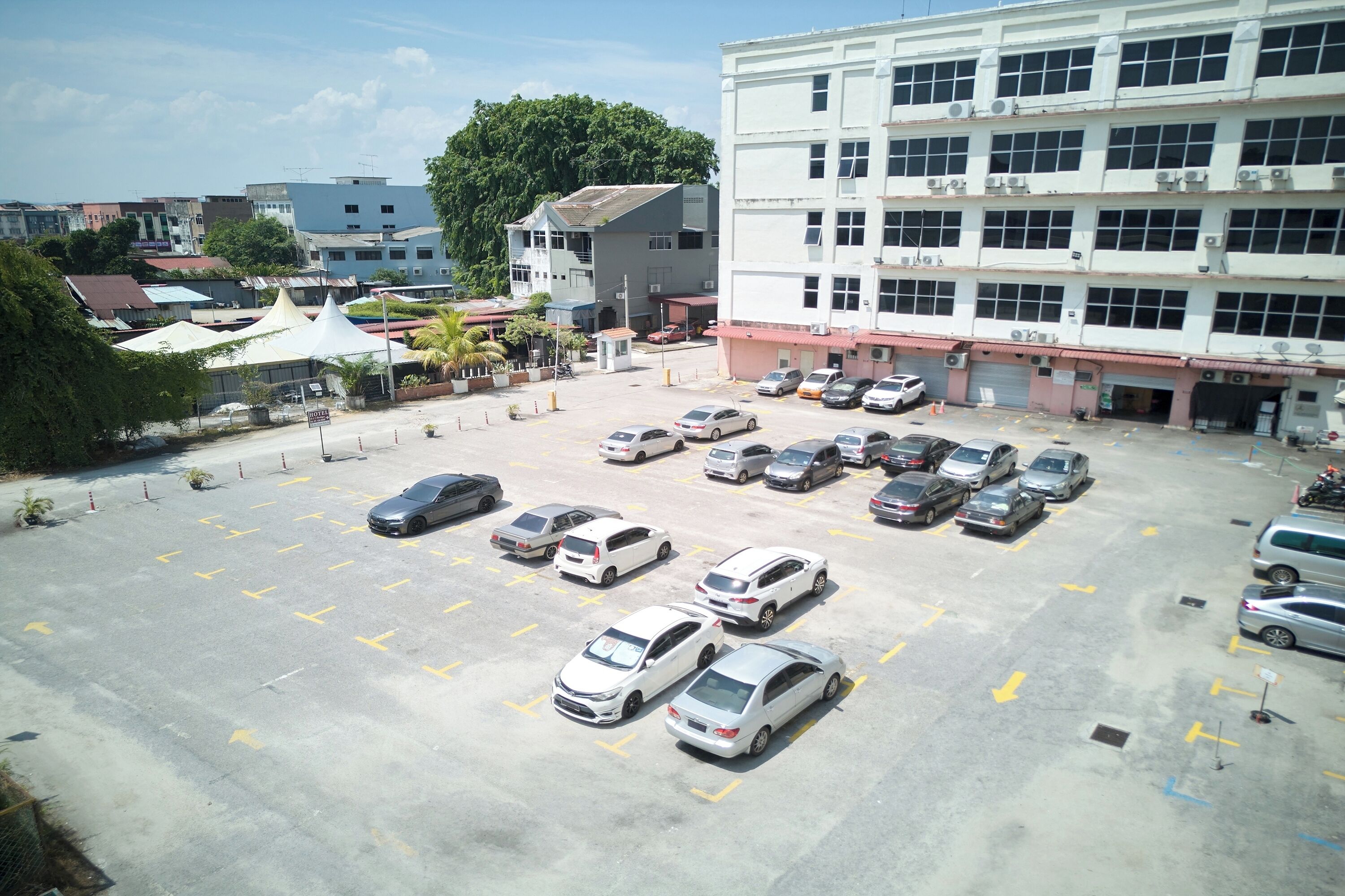 Un parking contenant de nombreuses voitures et un immeuble à plusieurs étages équipé de systèmes de climatisation.