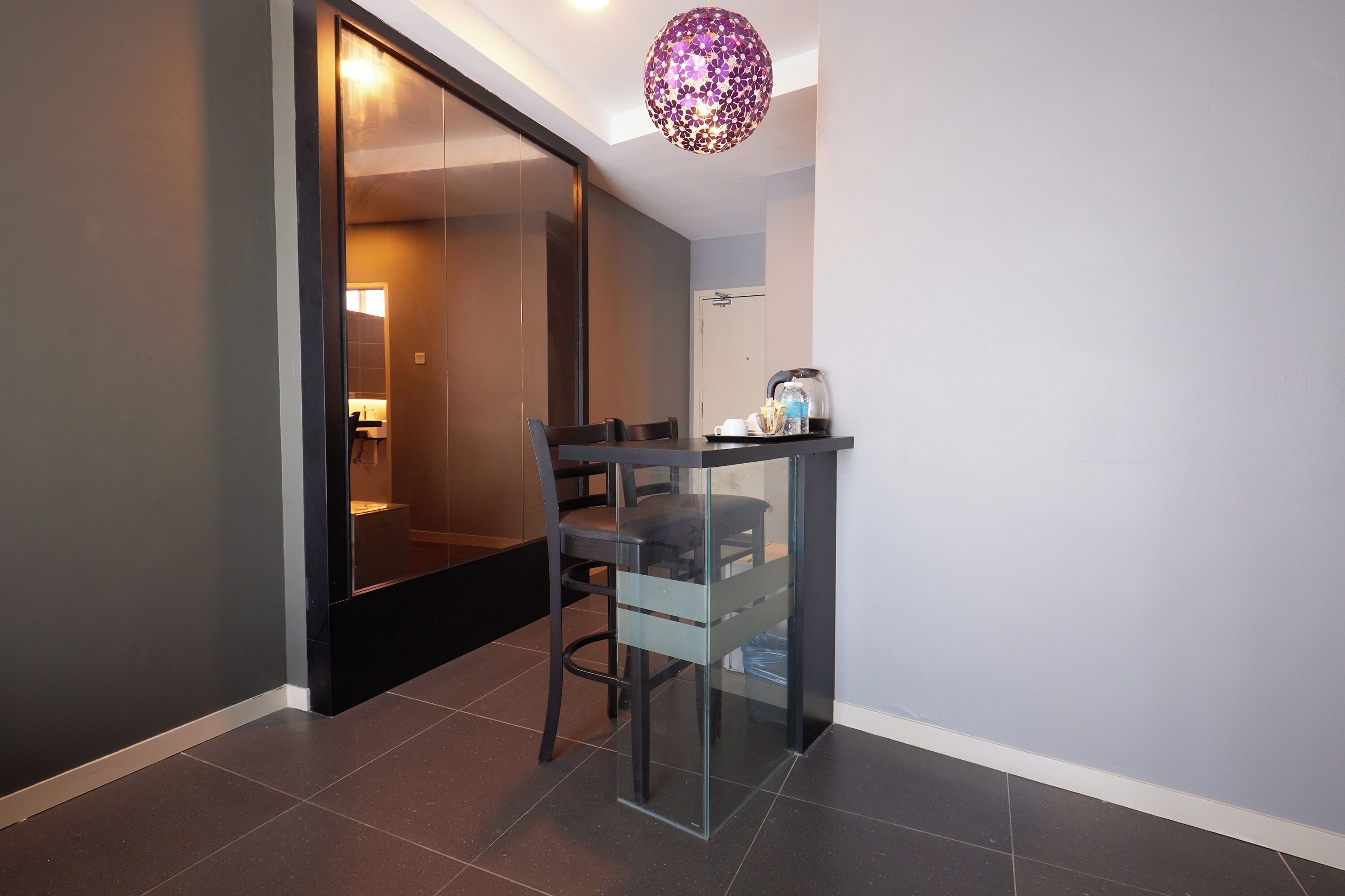 A modern dining area with a glass partition, a chair, and a small table with a tray of items.