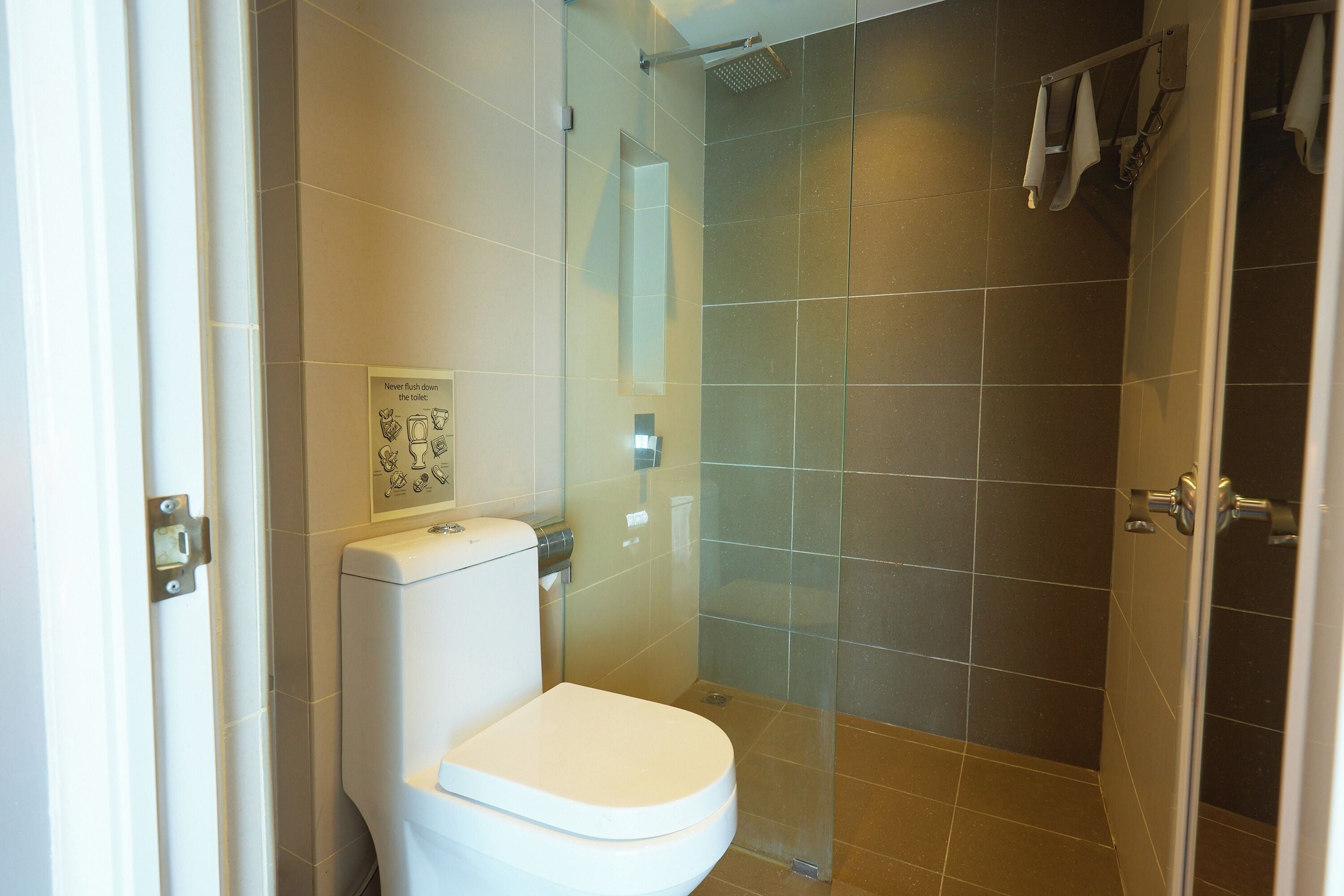 A modern bathroom with a toilet, a glass shower enclosure, and a towel rack.