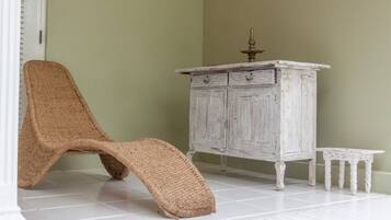 Una habitación con una silla blanca, un armario blanco y una pequeña mesa blanca.