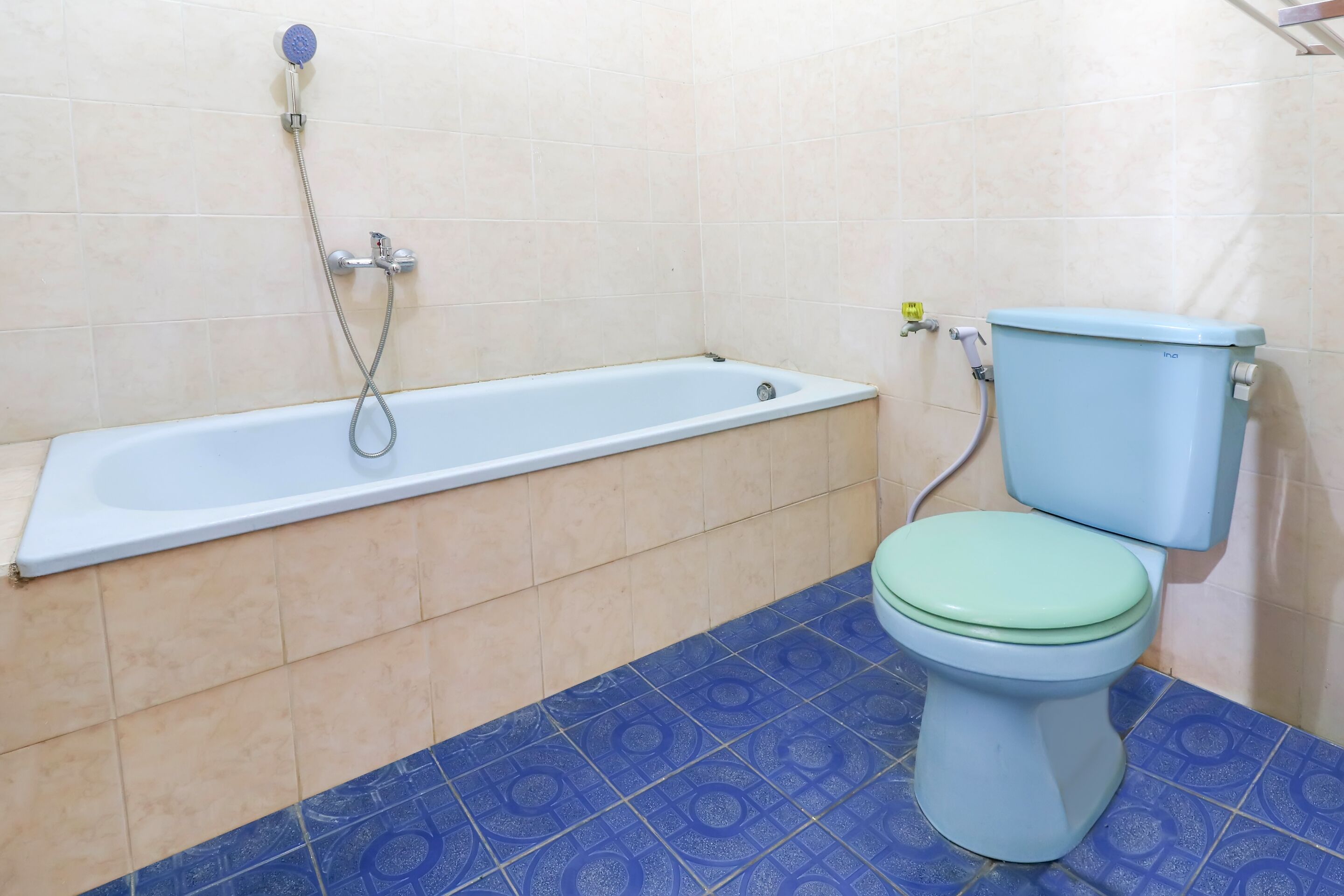 A bathroom with a bathtub, toilet, and blue patterned floor tiles.