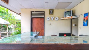 Un'area reception con un bancone in vetro, una porta in legno e la scritta "OYO" sulla parete.