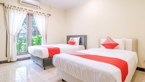 Camera d'albergo con due letti, entrambi con biancheria bianca e dettagli rossi, un'ampia finestra con tende e un condizionatore d'aria a parete.
