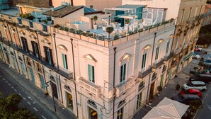 A multi-story building with a rooftop terrace, balconies, and a street view. - Caportigia Boutique Hotel (Syracuse)