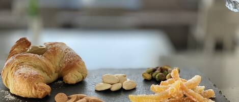 A croissant with almonds and sugar-coated almonds on a slate board.