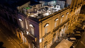 A multi-story building with a rooftop terrace featuring outdoor seating and a hot tub. - Caportigia Boutique Hotel (Syracuse)