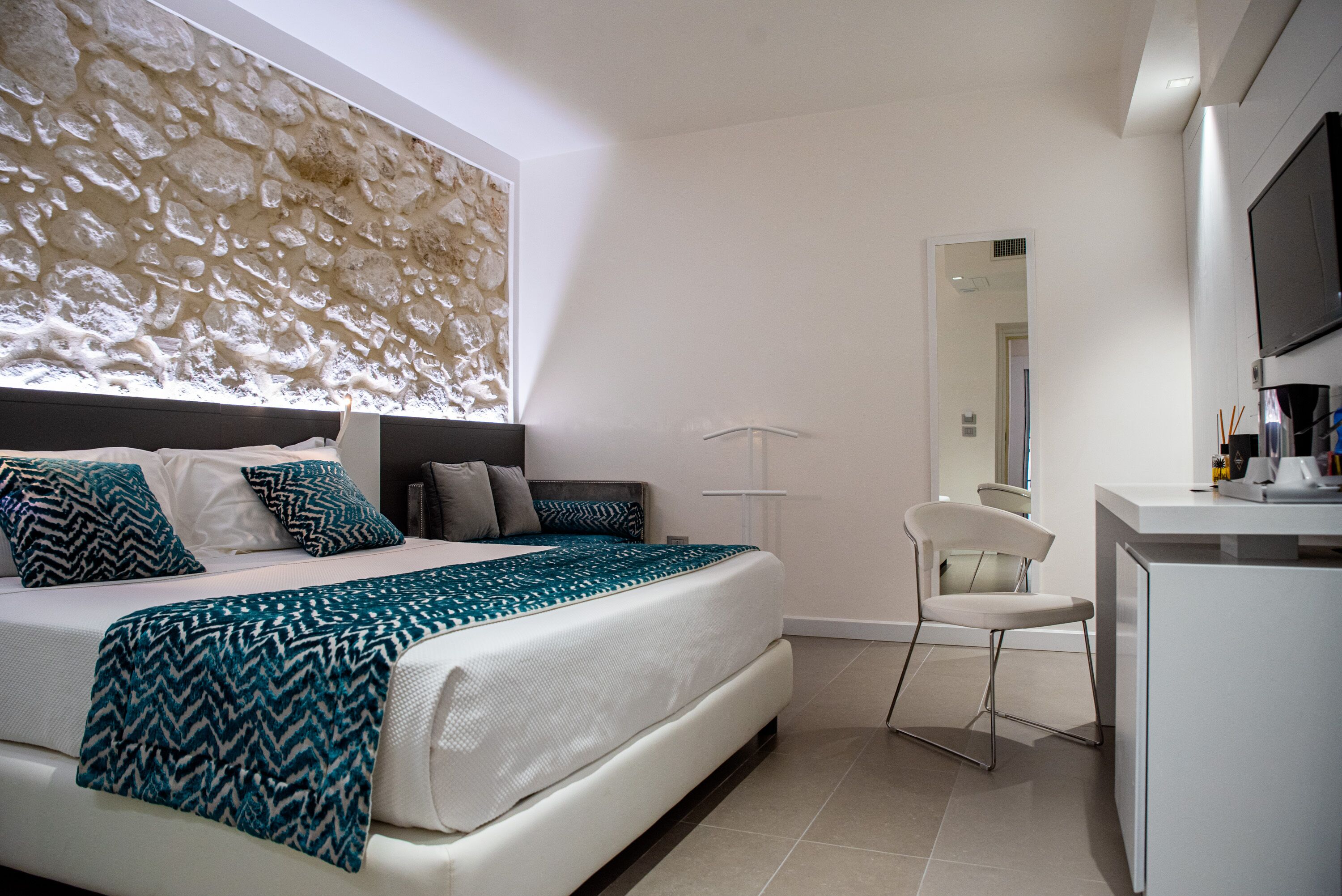 Une chambre moderne avec un grand lit, un bureau et un miroir.