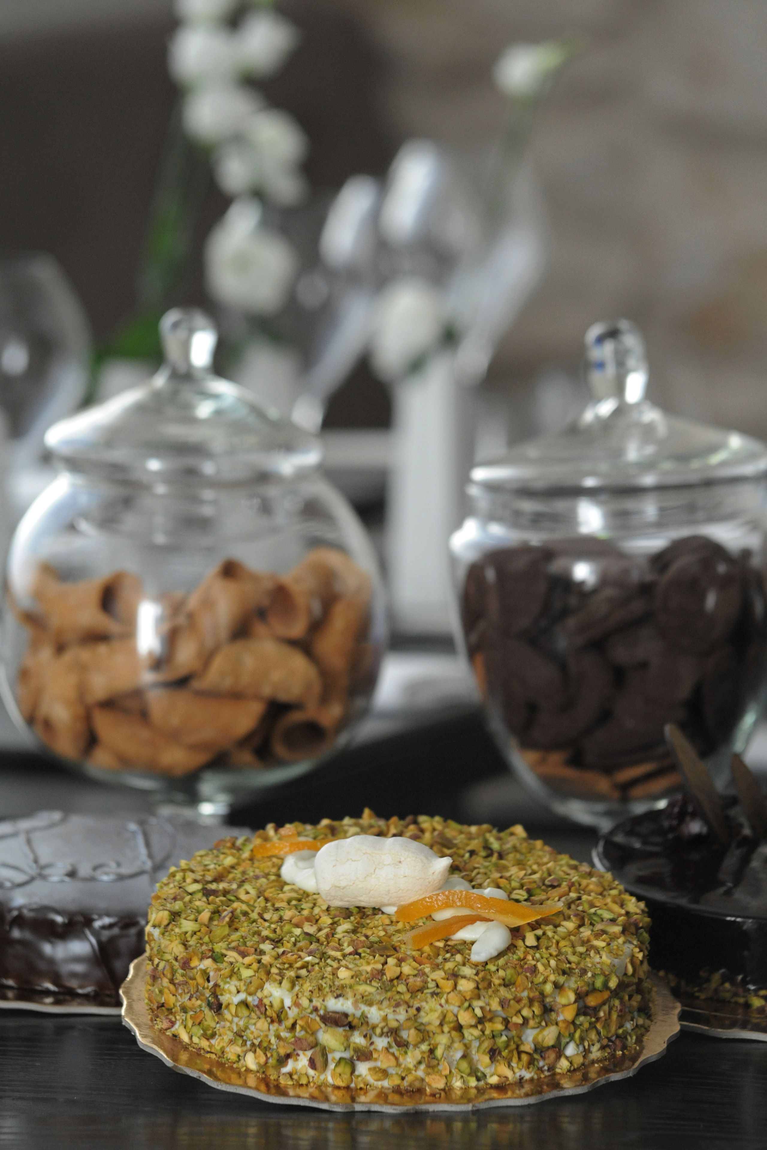 A dessert table with a nut-topped cake, two glass jars with dried fruits, and a chocolate dessert.