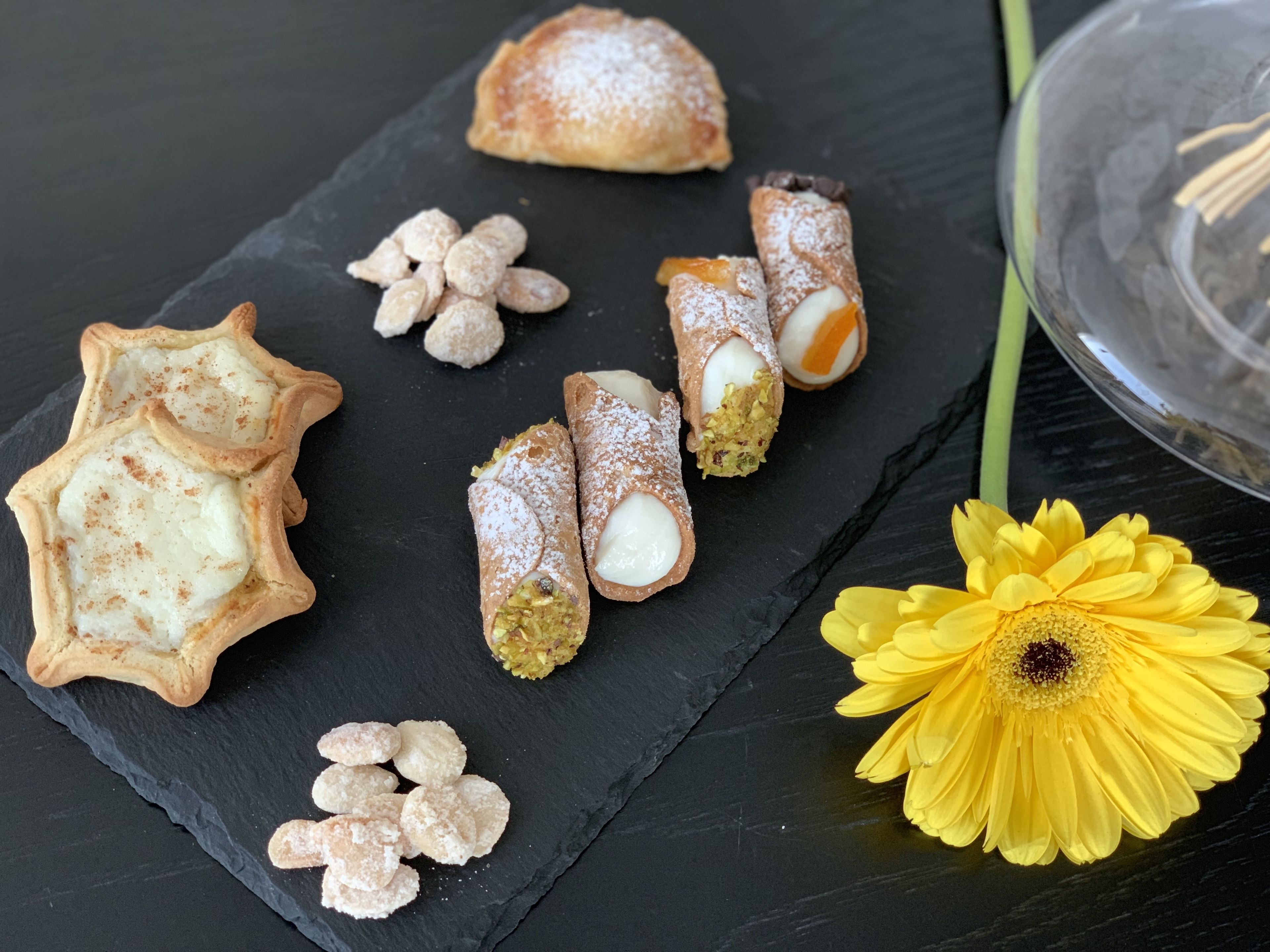 Variedad de pasteles en una tabla de pizarra, incluyendo un pastel con forma de estrella, pasteles rellenos enrollados y pasteles redondos espolvoreados con azúcar glas.