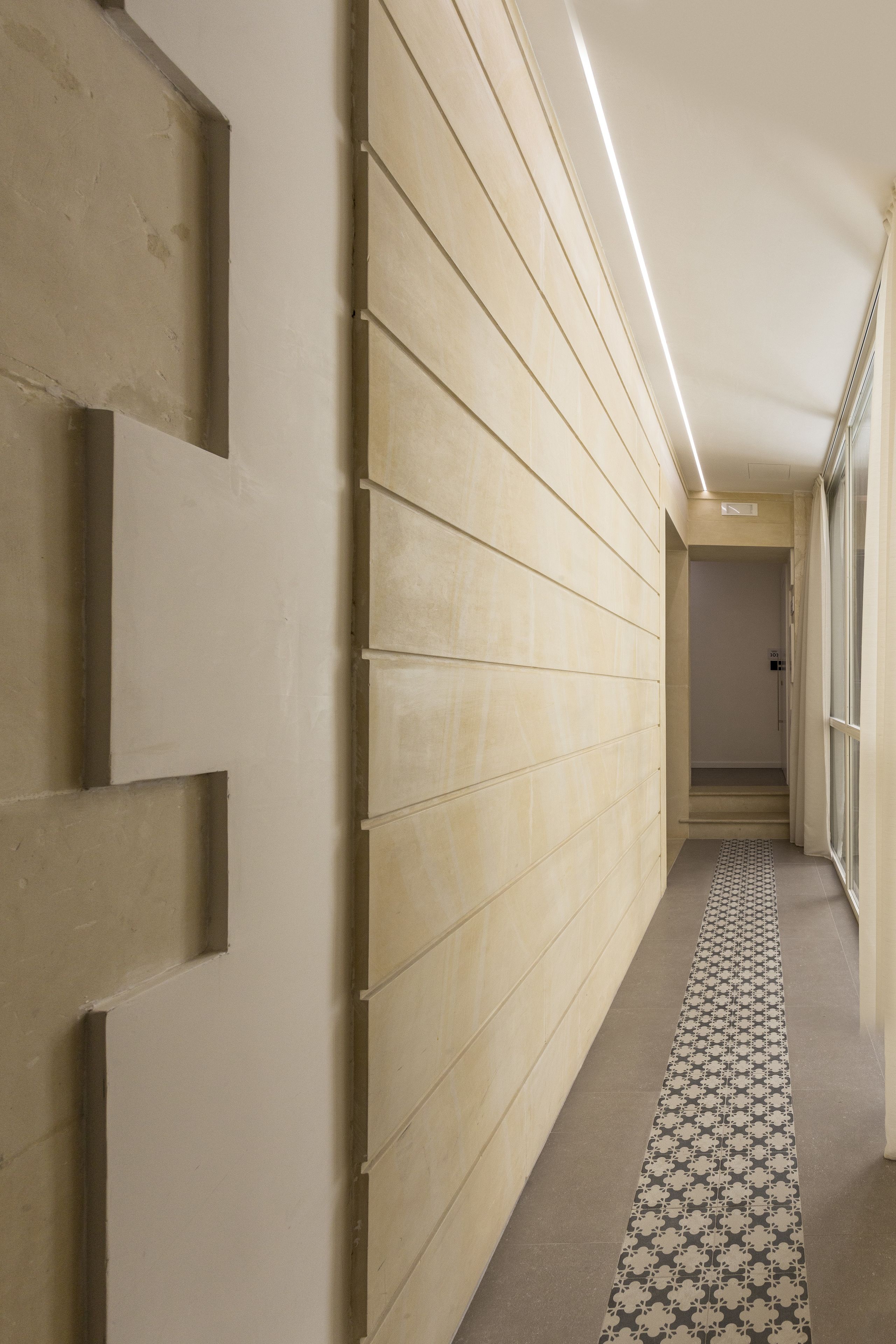 A hallway with beige paneling, a patterned floor, and a ceiling light.