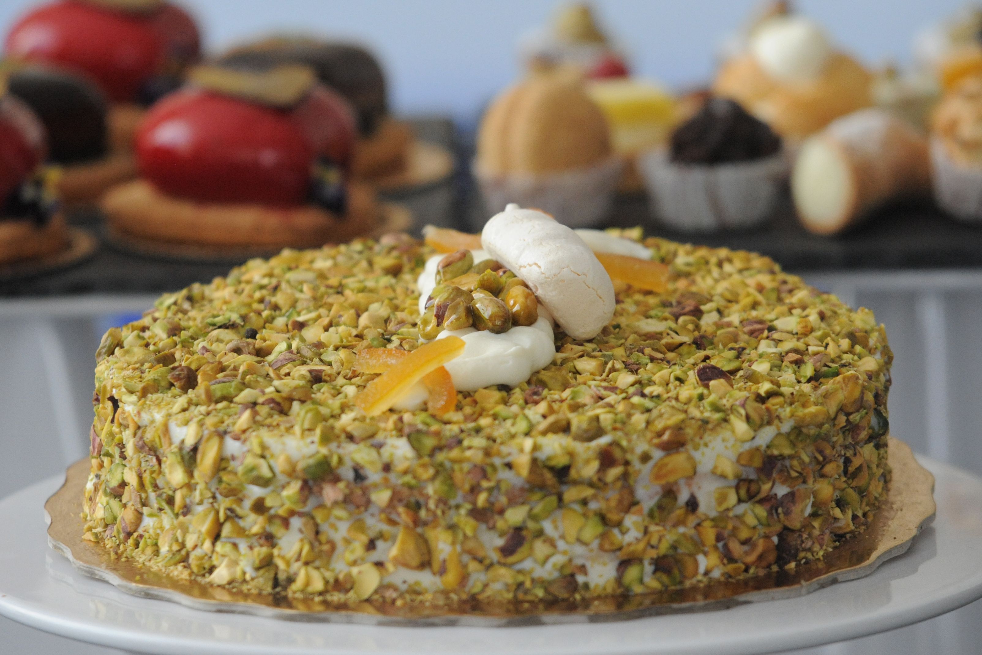 Un pastel redondo con nueces y una cucharada de crema por encima, sobre un plato blanco.