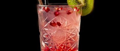 Ein klares Glas mit geometrischem Muster, gefüllt mit einem Getränk, einer Kiwischeibe und einem Strohhalm.