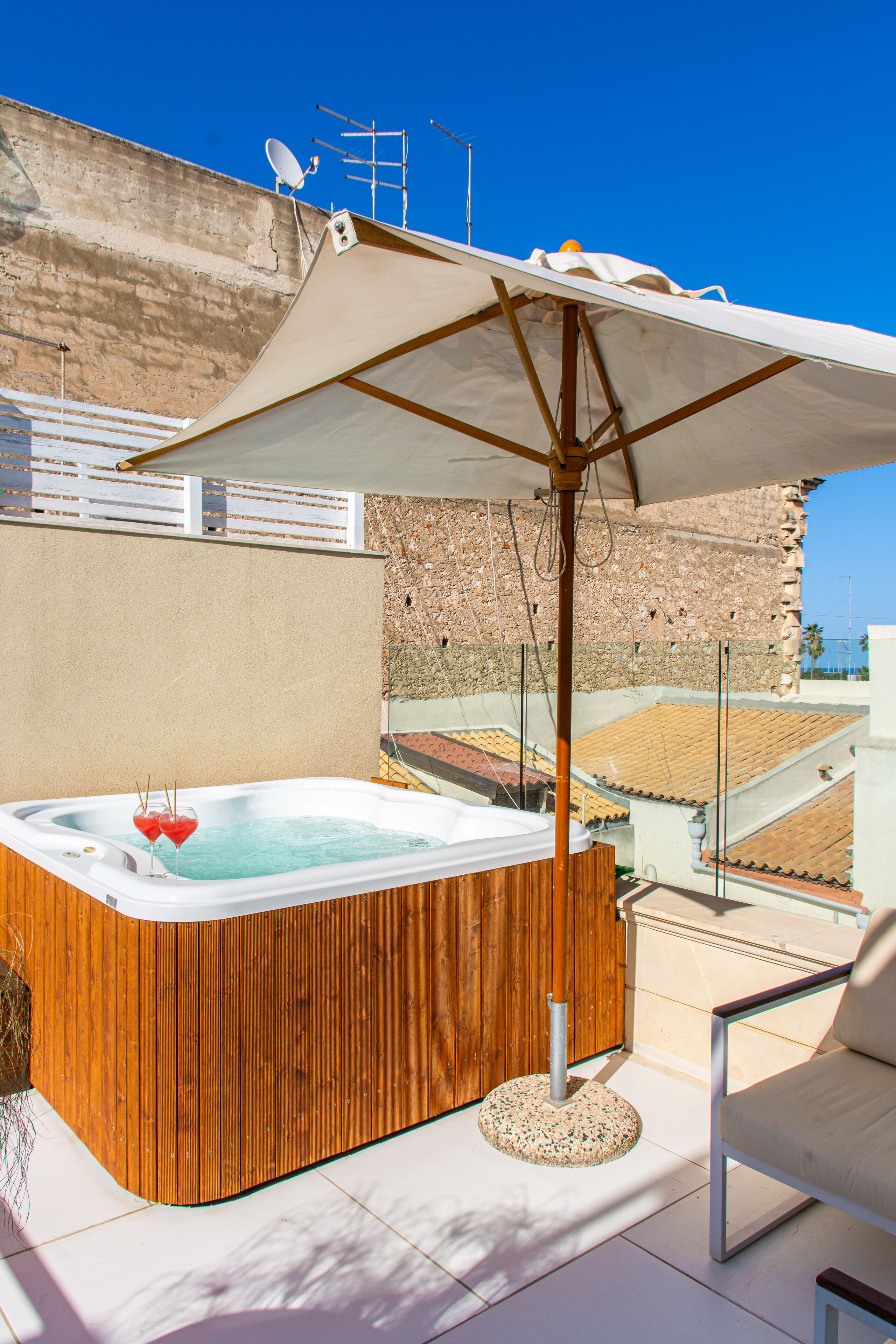Un bain à remous en bois, doté d’un auvent, d’une chaise et d’un mur de pierres en arrière-plan.