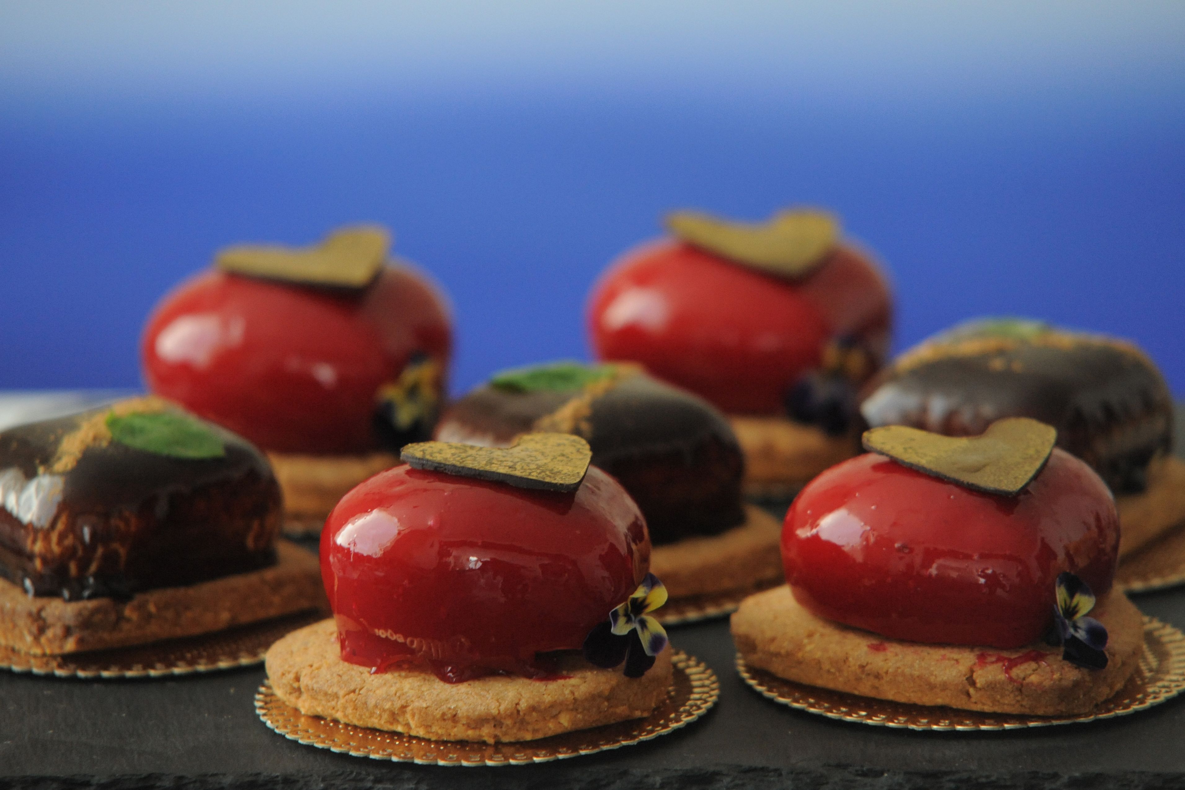 Un'esposizione di dolci con diverse torte e pasticcini su un vassoio in ardesia.