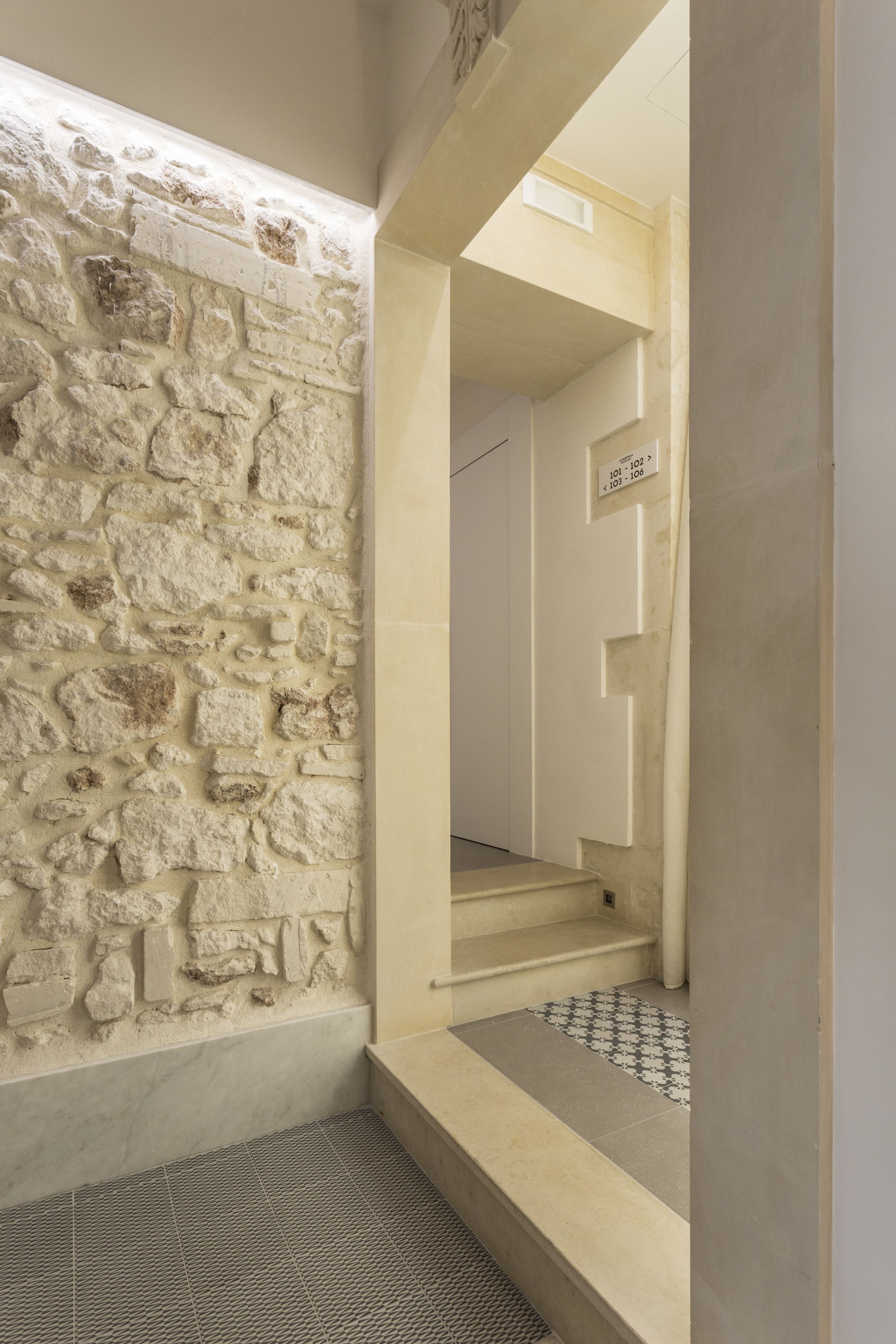 A stone wall, a tiled floor, and a staircase leading to a room.