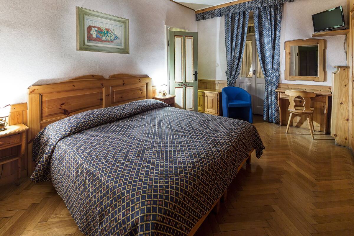 Ein Schlafzimmer mit einem hölzernen Bett, einem Schreibtisch, einem Stuhl und einem Fernseher.
