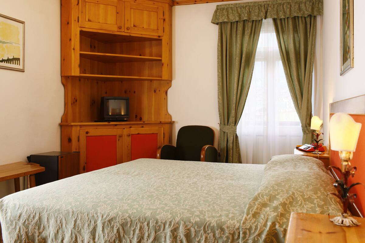 Ein Schlafzimmer mit einem Bett, Holzregalen, einem Sessel, einem Schreibtisch und einer Lampe.
