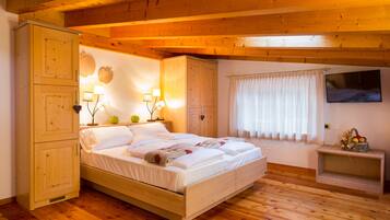 Camera da letto in legno con un letto, un armadio, un comodino e un tavolino con della frutta.