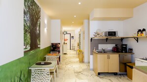 A modern kitchen with a microwave, coffee maker, and a sink. There is a dining area with a table and chairs. - Oasi Verde a San Pietro (Rome)