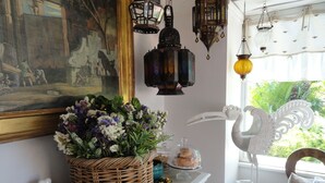 A room with a large painting, a wicker basket with flowers, a decorative bird sculpture, and a window with a view of greenery. - Le Lanterne B&B (Rome)