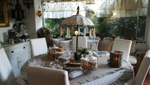 A dining area with a round table set for four, surrounded by white chairs. The table is covered with a white tablecloth and features various food items and glassware. - Le Lanterne B&B (Rome)