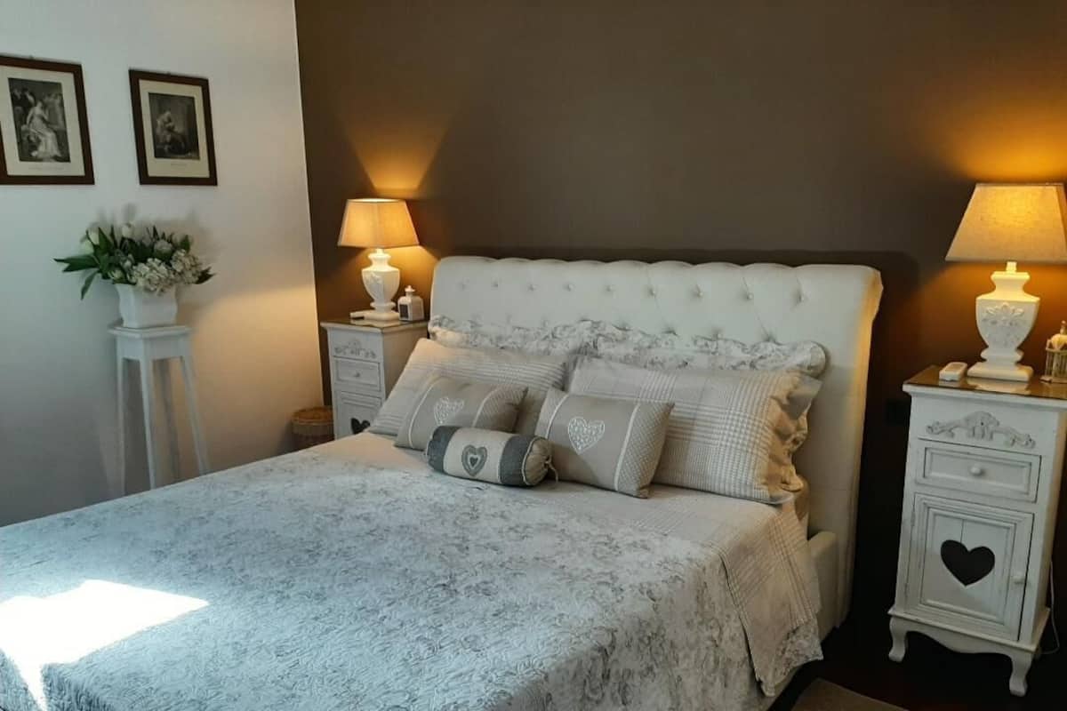 A bedroom with a tufted headboard, a floral-patterned bedspread, and two bedside tables with lamps.
