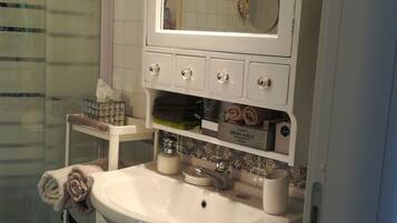 A bathroom with a white sink, a mirror, and a shower area.