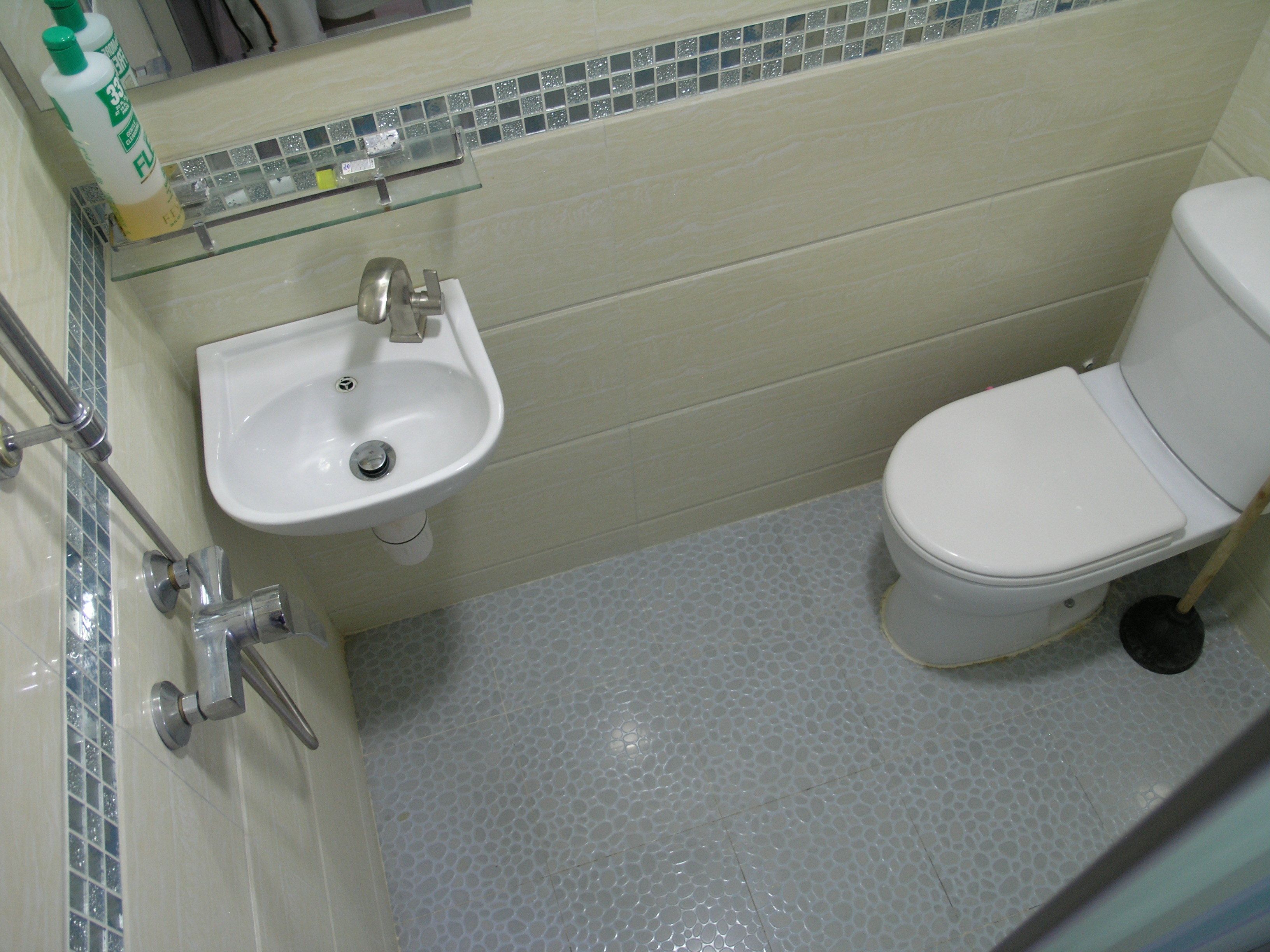 Een badkamer met een witte wastafel, toilet en een glazen plank erboven.