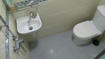 Een badkamer met een witte wastafel, toilet en een glazen plank erboven.
