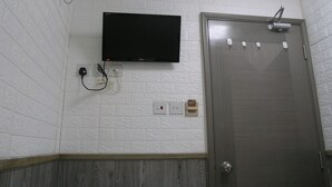 Une salle de bain équipée d’un téléviseur à écran plat fixé au mur, d’une porte avec un porte-serviettes et d’un sèche-mains.