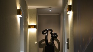 Un passadís amb un rètol del número 33, una escultura i llums penjades a la paret.